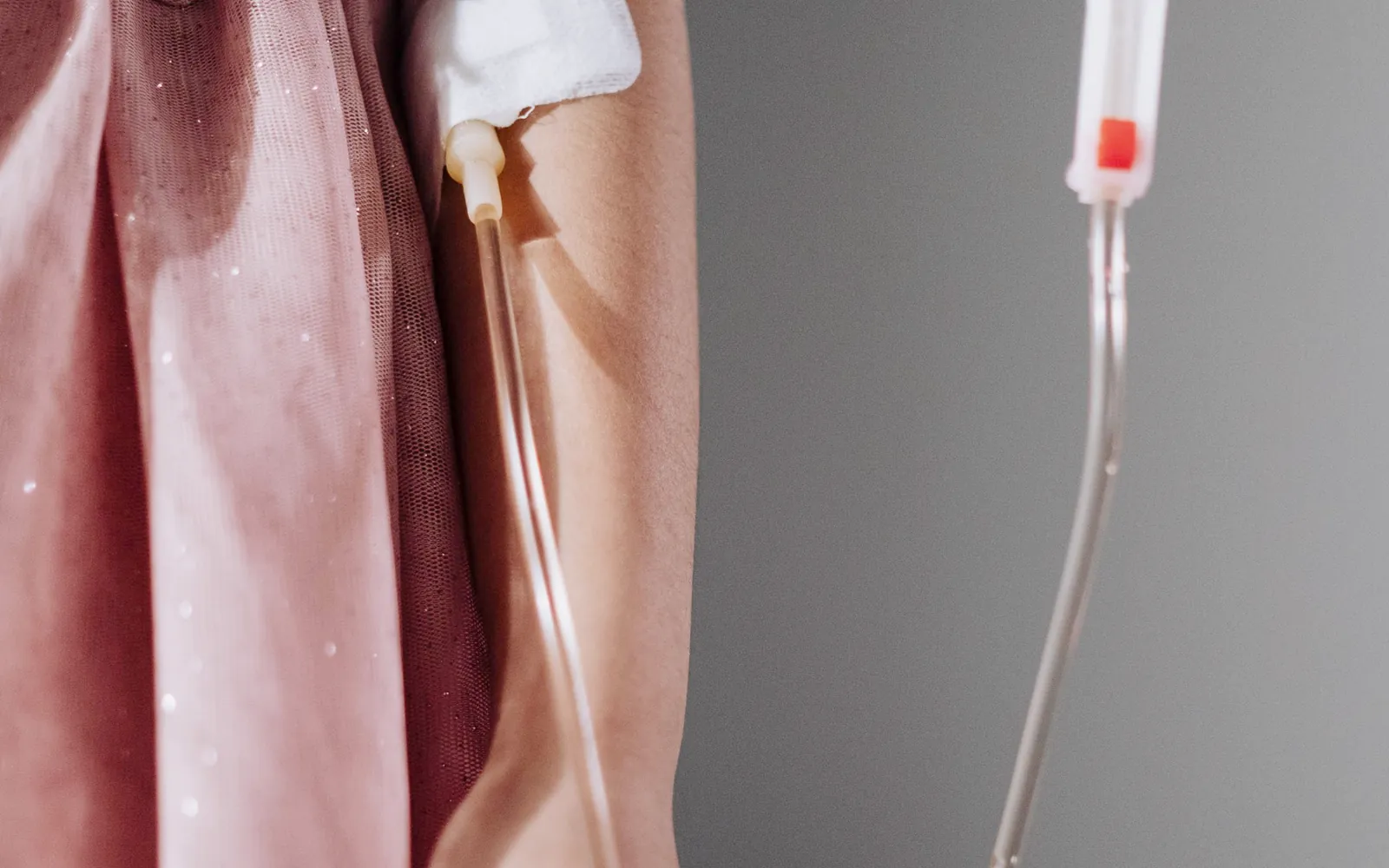 Infusion am Arm einer Frau in einem rosafarbenen Kleid