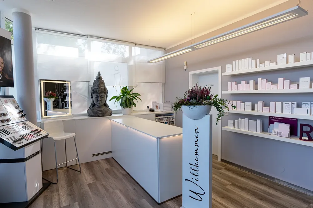 Empfangstresen mit Willkommen-Stele, Buddha-Figur und Produktregal
